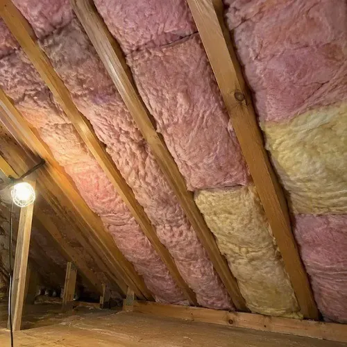 Batt insulation between sloped attic ceiling rafters during insulation and drywall work in Kingston, ON