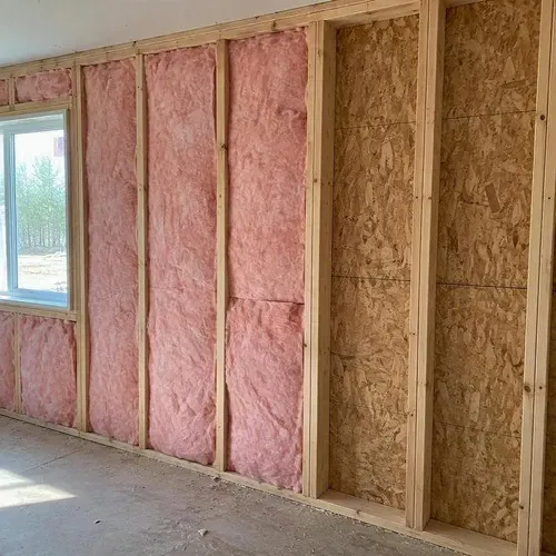 Partially insulated exterior wall with empty bays during insulation and drywall work in Kingston, ON
