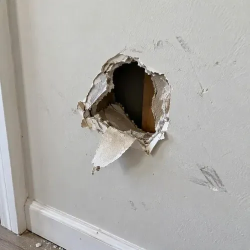 Hole in drywall with piece dangling on a drywall repair job in Kingston, ON