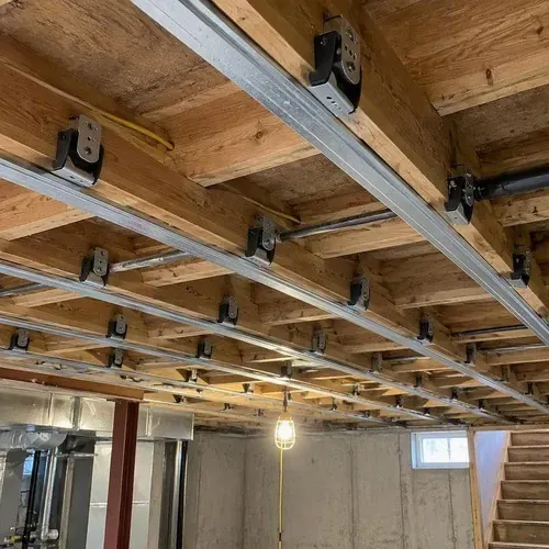 Sound isolation clips and hat channel installed on a basement ceiling for drywall soundproofing in Kingston