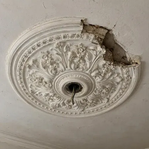 Broken corner of a plaster ceiling rose during plaster crown moulding repair in Kingston, ON