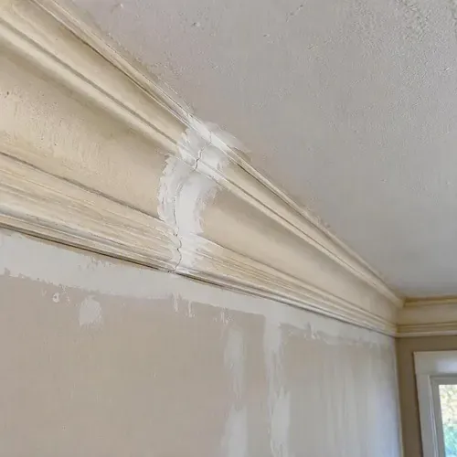 Fresh filler along a crown moulding joint during plaster crown moulding repair in Kingston, ON