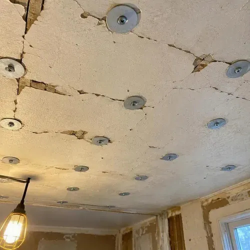 Plaster washers screwed into sagging ceiling during lath and plaster repair in a Kingston home