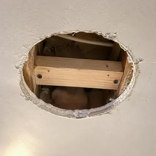 Backing block installed behind ceiling hole before patching during pot light hole repair in Kingston, ON