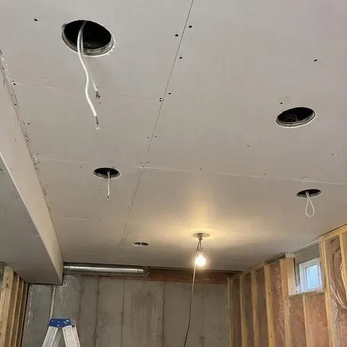 Row of open pot light holes across a basement ceiling before pot light hole repair in Kingston