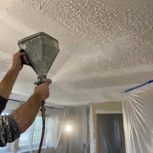 Hopper gun spraying matched texture onto a repaired ceiling in a Kingston home