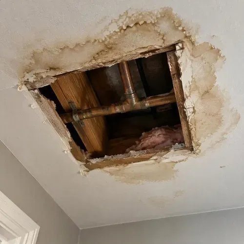 Ceiling opened up around a leaking pipe during water damage drywall repair in Kingston, ON