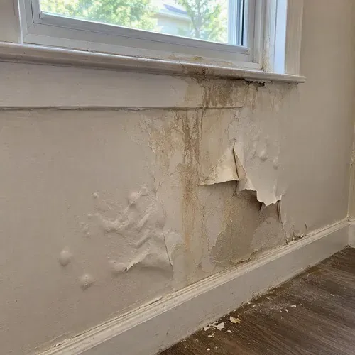 Paint peeling and drywall bubbling under window during water damage drywall repair in Kingston, ON